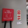 Ultrafire fire blanket in red container mounted on wall with instruction label next to it