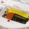 Back closeup view of kidde firex mains powered optical smoke alarm alkaline battery backup showing warning and caution labels