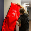 Person lifting the UltraFire Descender cover off the evacuation chair mounted on a wall