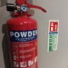 Ultrafire powder fire extinguisher 2kg shown upright fixed to a wall with safety instructions visible nearby